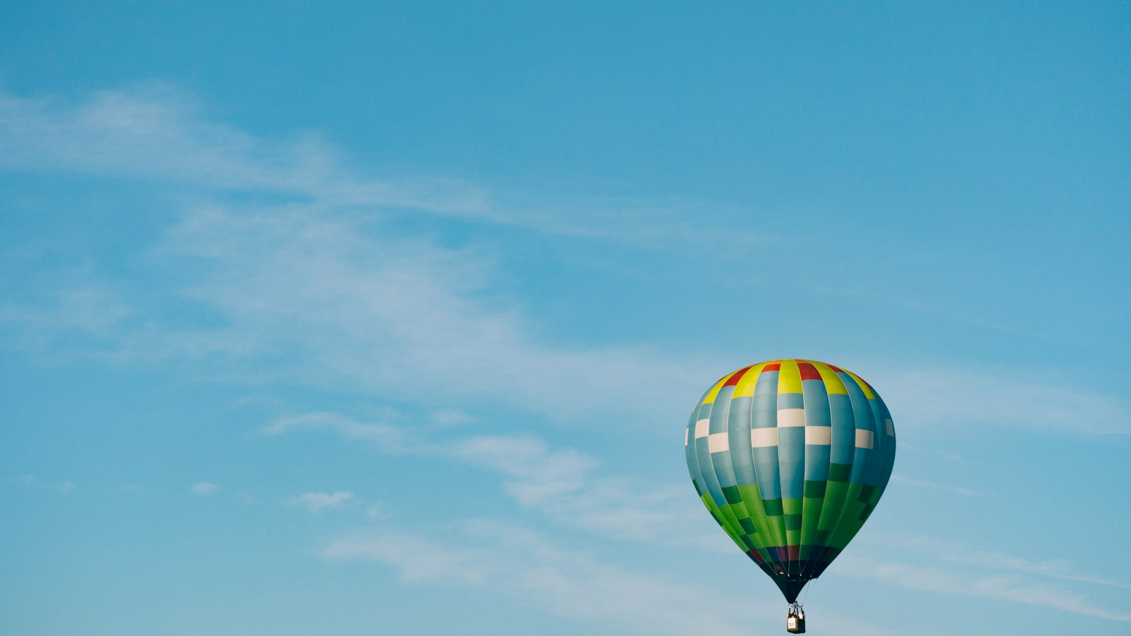 Decorative element: Multi-coloured hot air balloon in the blue sky on a sunny day