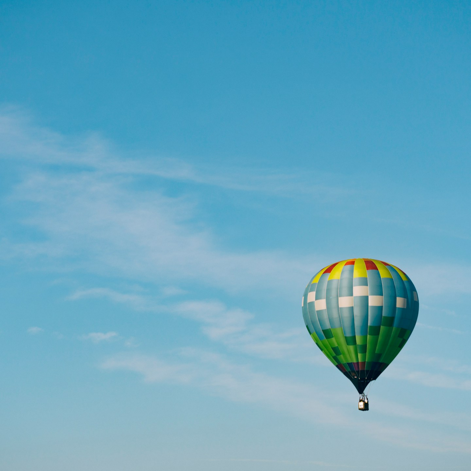 Decorative element: Multi-coloured hot air balloon in the blue sky on a sunny day