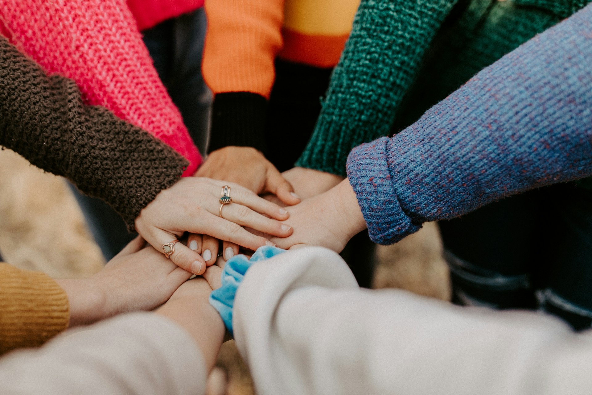 People in a circle putting their hands together in the middle