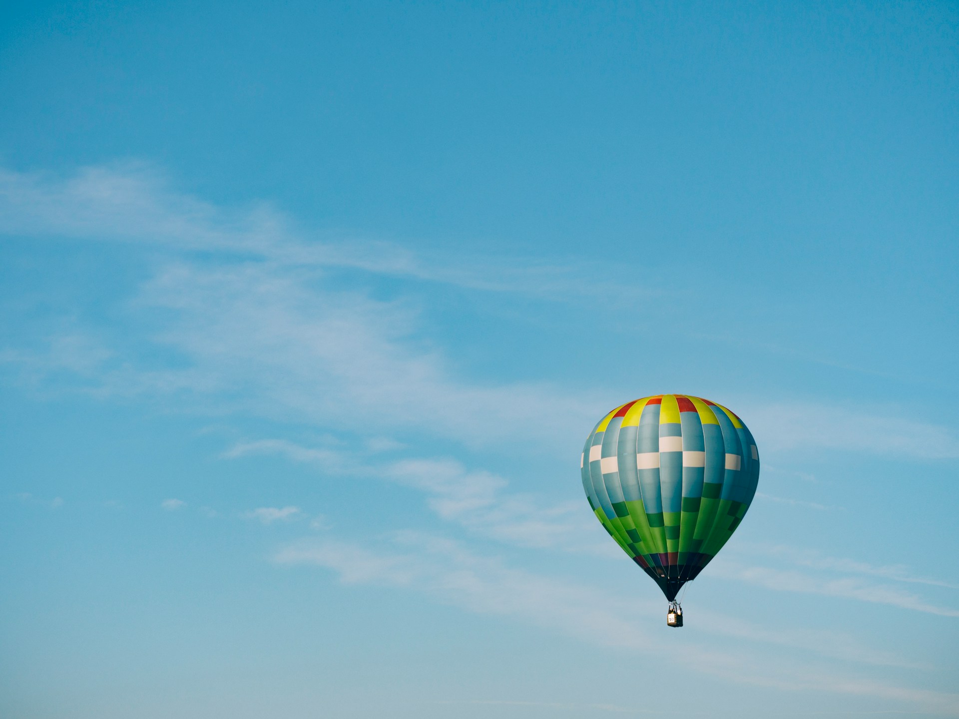 Decorative element: Multi-coloured hot air balloon in the blue sky on a sunny day